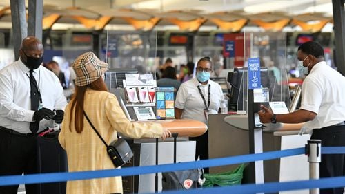 Travelers wearing face masks check in through plexiglass dividers at Delta counters at Hartsfield-Jackson International Airport on Thursday, July 2, 2020.(Hyosub Shin /Hyosub.Shin@ajc.com)