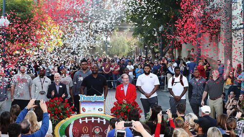 Confetti flies  over Oklahoma (left) and Georgia coaches and players during the welcome press conference at Disneyland Wednesday.