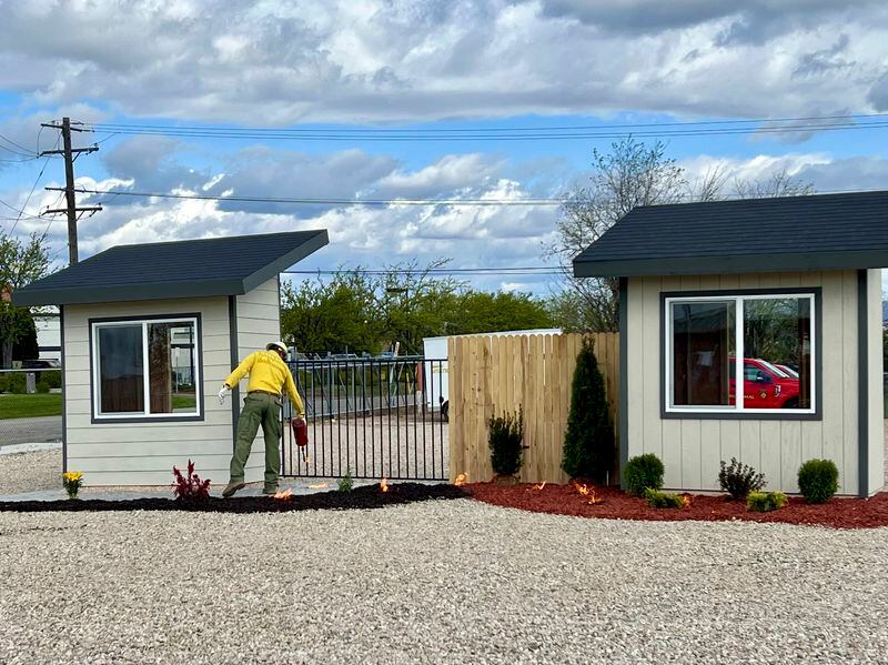 A firefighter uses a drip torch to simulate blowing embers during a burn demonstration for the National Association of Insurance Commissioners Western Zone at the National Interagency Fire Center in Boise, Idaho, Monday, April 29, 2924. The building on the left is designed to mimic a home built using fire-resistant materials with defensible space around the exterior, and the building on the right is designed to mimic a home with traditional landscaping and building materials. The building on the right quickly burned to the ground. (AP Photo/Rebecca Boone)