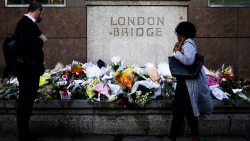 People look at the floral tributes placed at London Bridge to commemorate the victims of Saturday's attack in London, Tuesday, June 6, 2017. British police on Tuesday named the third London Bridge attacker as an Italian national of Moroccan descent, and Italian officials said they had passed on their concerns about him to British intelligence officials last year. (AP Photo/Markus Schreiber)
