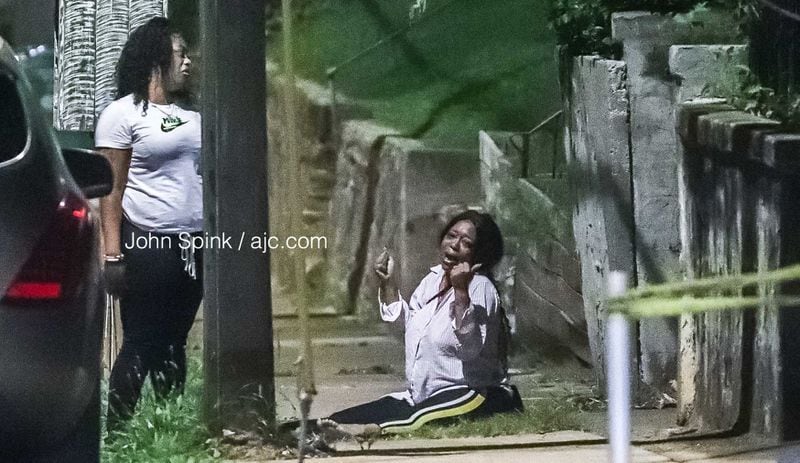 A woman cries on the sidewalk following an overnight shooting that left two people dead outside a house party in Vine City.
