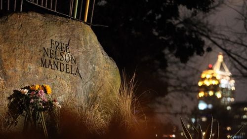 Flowers left by well-wishers lean against the "Free Nelson Mandela" sculpture in Piedmont Park on Thursday night, Dec. 5, 2013 in honor of the former South African president who died earlier in the day.