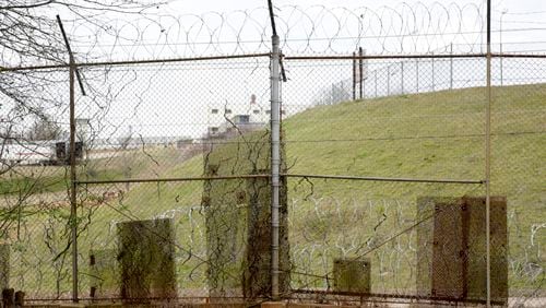 Patches of metal cover holes that minimum-security inmates have cut into  the fence around the Atlanta federal penitentiary's prison camp as they escaped and then sneaked back in. (David Barnes / For the AJC)