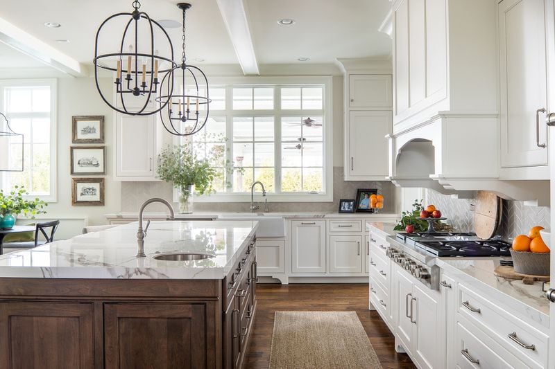 In an example of shifting away from modern farmhouse, this kitchen incorporates a wood island and lighting that breaks that style. Photo: Courtesy of Tara Fust Design / David Cannon Photography