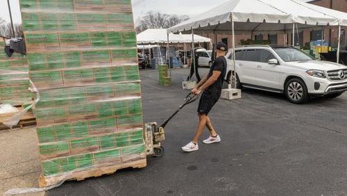 Dayton Gordo moves a pallet of 200 Girl Scout cookies to be loaded into vehicles during the Count-N-Go Cookie Caravan event in Roswell on Saturday, Feb 10, 2024. (Steve Schaefer/steve.schaefer@ajc.com)