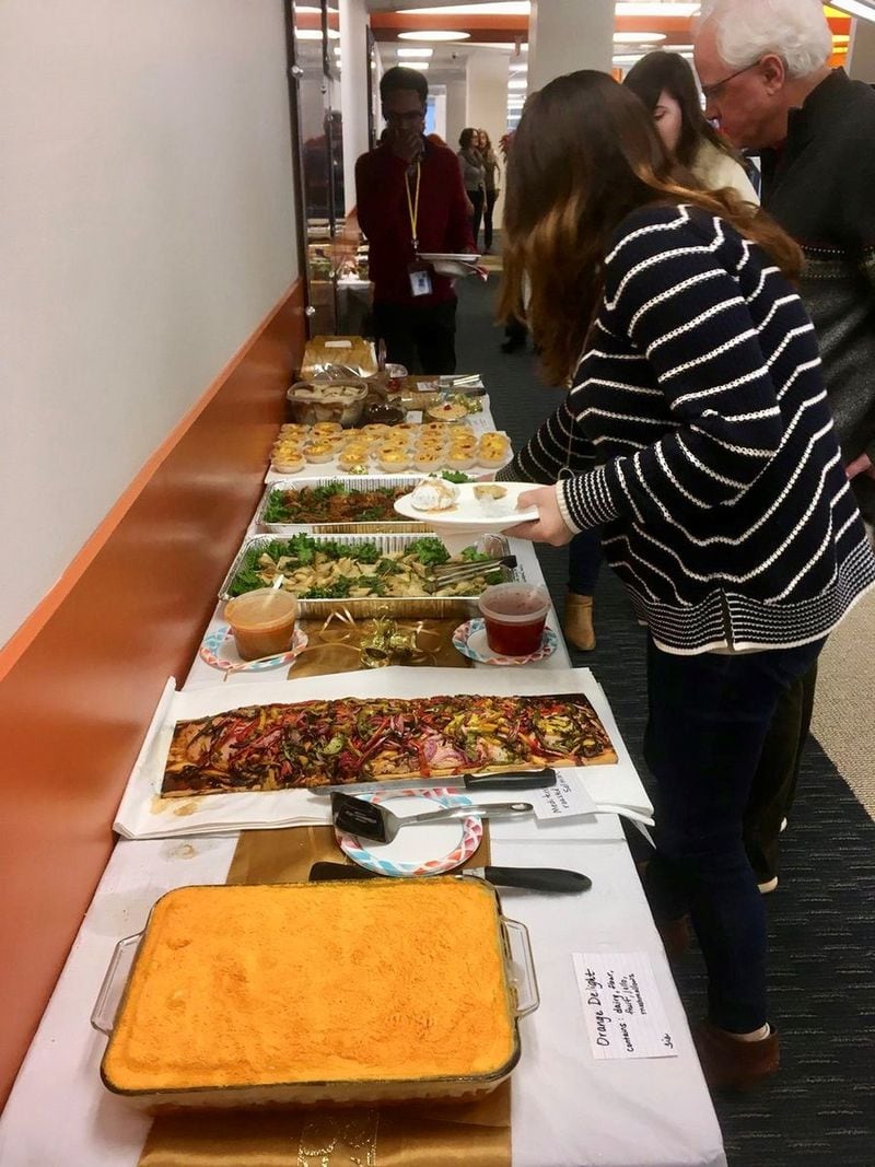 AJC staff fill their plates at the annual holiday potluck. That’s reporter Tia Mitchell’s Orange Delight in the foreground. It tastes of the 1970s, Mitchell said of her retro dessert, made from dairy, fruit, Jell-O and marshmallows. JENNIFER BRETT/JENNIFER.BRETT@AJC.COM