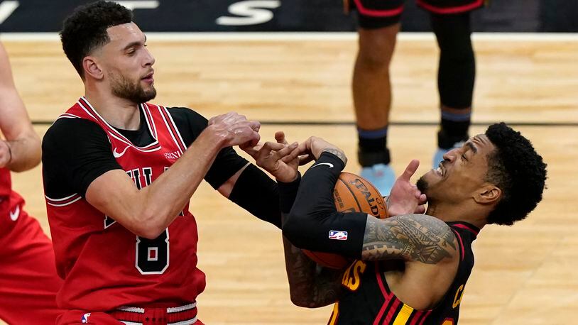Hawks' John Collins (right) battles for a rebound against Chicago's Zach Lavine during the first half of the season opener against the Bulls Wednesday, Dec. 23, 2020, in Chicago. (Nam Y. Huh/AP)