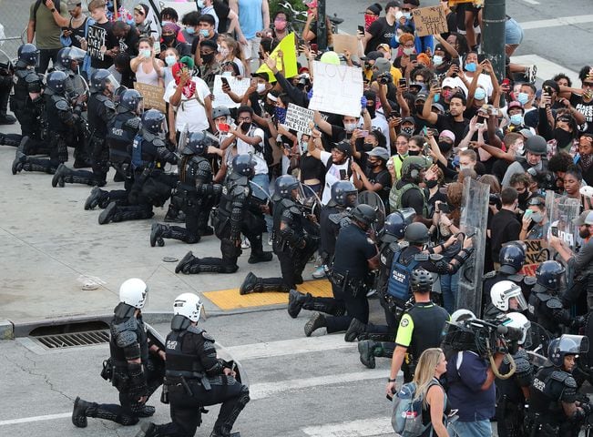 060120 Atlanta: In a show of peace and solidarity law enforcement officials with riot shields take a knee before protesters during a fourth day of protests over the death of George Floyd on Monday, June 1, 2020, in Atlanta.     Curtis Compton ccompton@ajc.com
