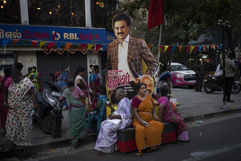 Supporters rest by a large cut out of Dravida Munnetra Kazhagam leader and Chief Minister of Tamil Nadu state, M. K. Stalin, following an election rally in the southern Indian city of Chennai, April 17, 2024. (AP Photo/Altaf Qadri)
