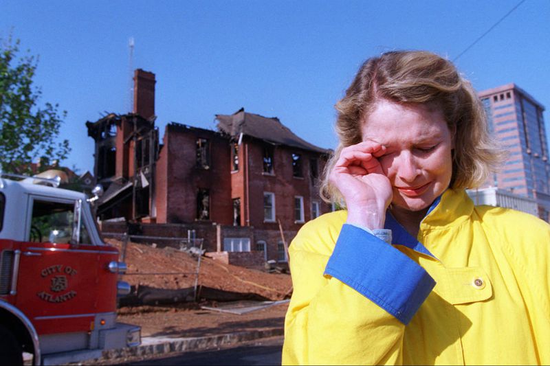 In May of 1996, when the renovated Margaret Mitchell house was almost ready to open its doors to the Olympic Games crowd, arsonists burned the Midtown building. A distraught Mary Rose Taylor, founder of the project, stood outside the smoking ruins, and vowed to rebuild. (AJC Photo/Dwight Ross Jr.)