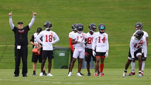 Atlanta Falcons head coach Dan Quinn gives his wide receivers group, missing Julio Jones, a double thumbs up as they run receiving routes for the quarterbacks on the first day of mandatory mini-camp on Tuesday, June 12, 2018, in Flowery Branch.