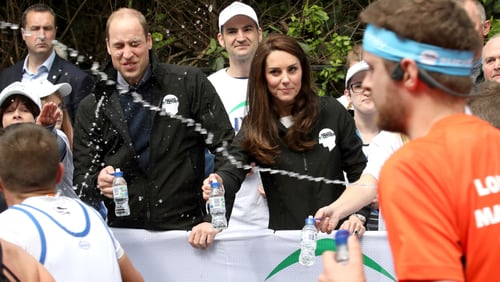 A runner squirts water towards Britain's Prince William, the Duke of Cambridge, as he hands out water to runners during the London Marathon in London, Sunday.