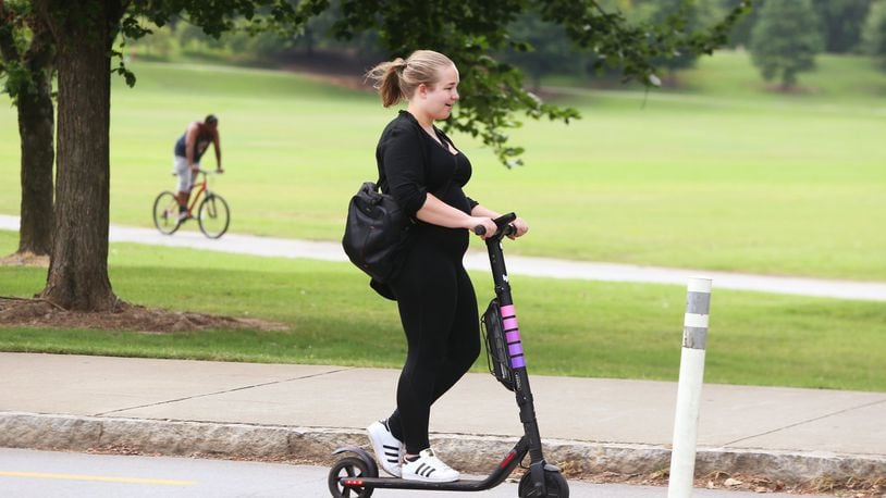 A woman rides a scooter by Piedmont Park in Atlanta on Wednesday, July 18, 2019. Many Atlantans have embraced e-scooters, while others complain that they violate pedestrians’ right of way. Atlanta City Council approved regulations on the scooters at the beginning of 2019, requiring companies to prevent them from being scattered haphazardly on city sidewalks. (Christina Matacotta/Christina.Matacotta@ajc.com)