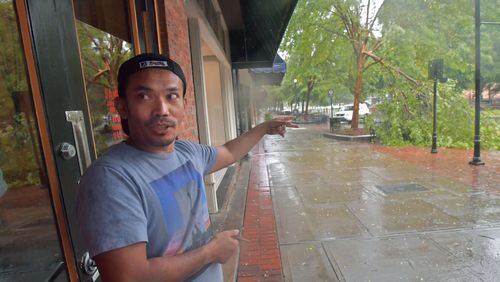 Saban Nadeak, owner of Samurai Japanese restaurant in Columbus, shows where the tree fallen onto his car on Monday. HYOSUB SHIN / HSHIN@AJC.COM