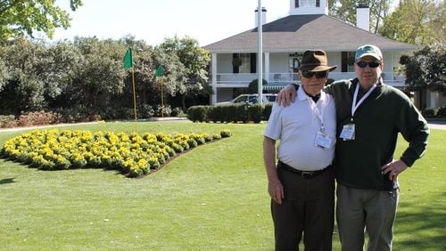 Cameras and cellphones are strictly forbidden at the Masters, but Augusta National does offer to take your picture in front of the clubhouse next to the iconic America-shaped flower bed. Pictured here, the author (right) with his father on their bucket-list trip to last year’s tournament. BLAKE GUTHRIE