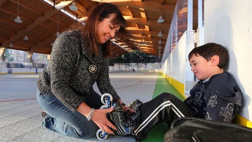 Wendy Pyles helps her son Hagan put on his skates at the roller hockey rink at Pinckneyville Park in Norcross in this 2013 file photo.