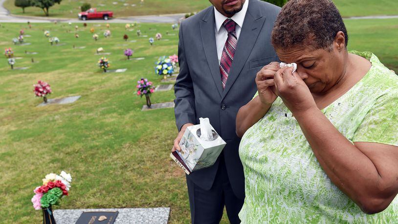 Freda Waiters is comforted by Rev. Vizion Jones during a visit to the gravesite of her son, Ariston. Aritston was shot and killed by a Union City police officer in 2011. BRANT SANDERLIN/BSANDERLIN@AJC.COM