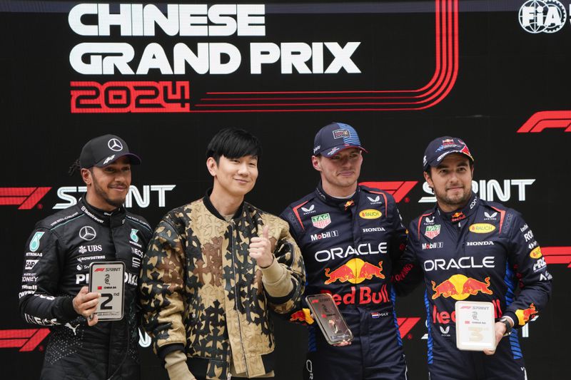 Singapore singer JJ Lin, second left, stands with sprint race winner Red Bull driver Max Verstappen of the Netherlands, second placed Mercedes driver Lewis Hamilton, left, of Britain and third placed Red Bull driver Sergio Perez, right, of Mexico at the Chinese Formula One Grand Prix at the Shanghai International Circuit, Shanghai, China, Saturday, April 20, 2024. (AP Photo/Andy Wong)