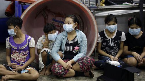 In this Nov. 9, 2015, photo, Eae Hpaw (center), 16, an undocumented child worker, sits with children and teenagers to be registered by officials during a raid on a shrimp shed in Samut Sakhon, Thailand. Ten children were taken to a government shelter for human trafficking. AP PHOTO / DITA ALANGKARA