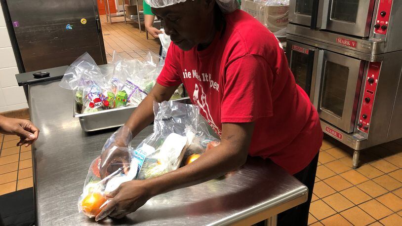 Zeborah (cq) Ogletree, a Clayton Schools nutritionist, prepares food Monday at North Clayton Middle School that will be distributed to the public.