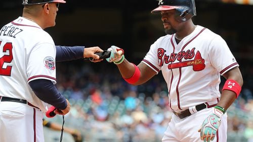 Braves second baseman Brandon Phillips, shown getting a fist bump from first-base coach Eddie Perez in a game last week, has missed consecutive starts for a right knee contusion but hopes to play Wednesday. (Curtis Compton/ccompton@ajc.com)