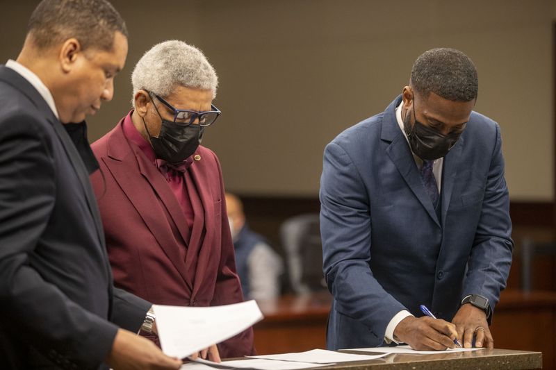 01/22/2021 —Marietta, Georgia — Cobb County Veterans Accountability and Treatment Court graduates Kenneth (right) and Edward (center) are asked by Cobb County District Attorney Flynn D. Broady Jr. (left) to sign a document that will expunge their records during their graduation ceremony at the Cobb County Superior Courthouse, Friday, January 22, 2021. Superior Court Judge C. LaTain "Tain" Kell presides over the Veterans Accountability and Treatment Court in Cobb Superior Court. (Alyssa Pointer / Alyssa.Pointer@ajc.com) [Last names are withheld by request of judge.]