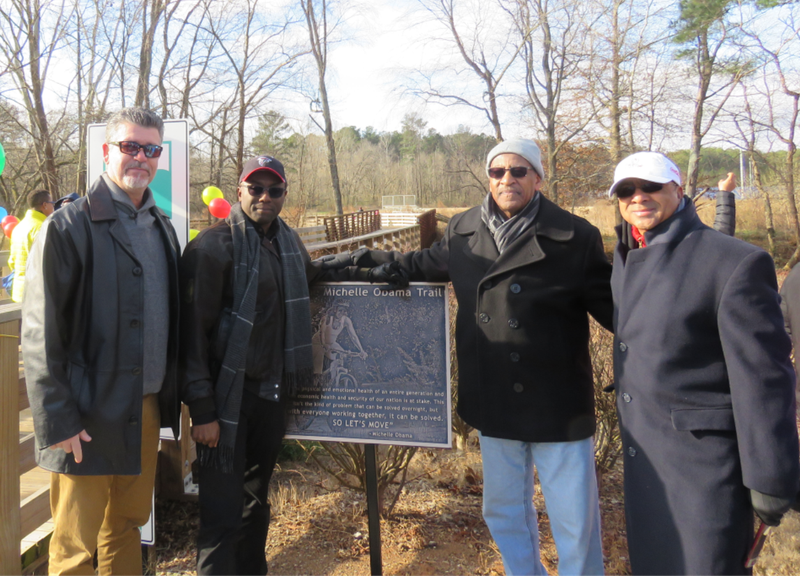 Rich Alvarez of First Tee of Atlanta, DeKalb Commissioner Larry Johnson, DeKalb County Recreation interim director Marvin Billups and Marvin Hightower of First Tee Atlanta pose next to a sign at the Michelle Obama Trail. (Photo courtesy of DeKalb County)
