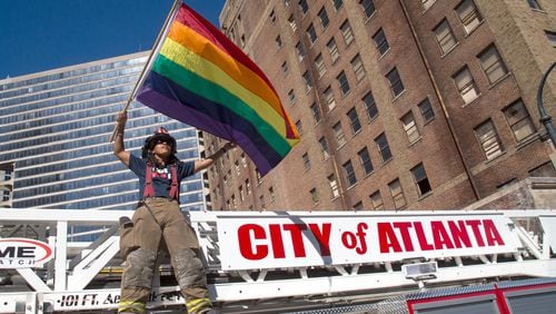 An Atlanta firefighter waves a Rainbow Flag while standing on a fire truck at the start of the Atlanta Pride Parade in 2016.