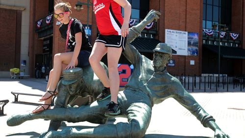 In this 2013 photo, sisters Natalie Banker, 13, left, and Carley, 11, of Gainesville, climb off of the bronze statue of MLB great Ty Cobb after their mother, Heather, took a photograph of them. AJC file