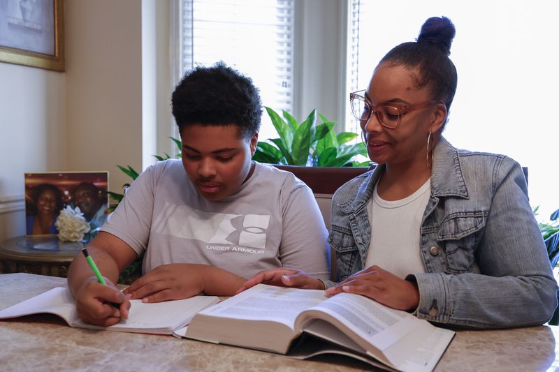 Adriane Burnett helps her son Josiah with his studies on Saturday, April 14, 2024 in Birmingham, Ala. Women's participation in the American workforce has reached a high point, but challenges around child care are holding back many working class parents. When women without college degrees face an interruption in child care arrangements – whether it's at a relative's home, a preschool or a daycare center – they are more likely to have to take unpaid time or to be forced to leave their jobs altogether, according to an Associated Press analysis. (AP Photo/Butch Dill)