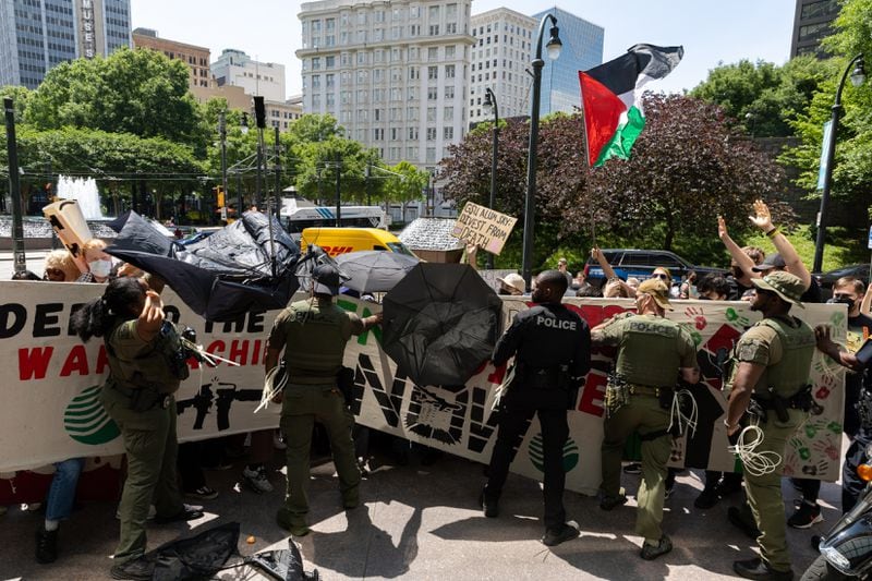 Pro-Palestinian activists and police scuffle in front of Georgia State University’s Andrew Young School of Policy Studies in Atlanta on Friday, May 3, 2024. The activists were protesting GILEE, which sends local police to train in Israel,  and is housed at the building. (Arvin Temkar / AJC)
