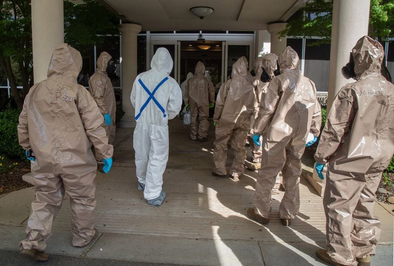 Members of the 265th Infectious Control GA Army National Guard enter a senior living facility in Buckhead Friday to clean the building. STEVE SCHAEFER / SPECIAL TO THE AJC