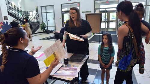April Bridges (center) and her daughter Lily Alcantara, 5, resister for kindergarten at Baggett Elementary School in Lawrenceville on Thursday, May 3, 2018. Gwinnett expects another record enrollment this year, and it devised a system to make the first day smoother by asking parents to fill out questionnaires about their kids beforehand. HYOSUB SHIN / HSHIN@AJC.COM
