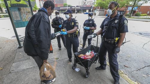 Atlanta Police Department officers distribute masks to the homeless at Hurt Park downtown on Friday, April 24, 2020. JOHN SPINK/JSPINK@AJC.COM