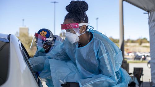 Two nurses work around a car with four individuals receiving COVID-19 tests at a DeKalb County Department of Health COVID-19 drive-thru testing site in Atlanta on November 17, 2020.  (Alyssa Pointer / Alyssa.Pointer@ajc.com)