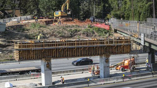 September 29, 2023 Atlanta: Construction work continued Friday, Sept. 29, 2023 on the new bridge construction as the existing Mount Vernon Highway bridge over I-285 in Sandy Springs will remain closed into next year after a tractor-trailer carrying an excavator crashed into it Wednesday, significantly damaging the bridge beams. Structural evaluations of the bridge were concluded Thursday evening, and it was determined that five of six beams were impacted and require replacement, according to Georgia Department of Transportation spokesperson Natalie Dale. Mount Vernon Highway will not reopen to vehicle or pedestrian traffic until summer 2024. “Safety of the traveling public is paramount in all Georgia DOT decisions,” Dale said. “GDOT is working with the contractor and evaluating all viable options to advance the current project timeline.” Authorities closed the bridge and the westbound I-285 lanes below after the truck clipped the overpass around noon Wednesday, snarling traffic during the evening commute and beyond. The damaged portion was secured overnight to prevent debris from falling onto the interstate, and all lanes of I-285 West reopened around 4 a.m. Thursday. The quickest way to get around the Mount Vernon Highway closure is to use Riverside Drive. Long Island Drive and Roswell Road are also good alternates, the WSB 24-hour Traffic Center reported. According to GDOT, the truck and equipment involved in the wreck were not related to the construction crews already in the area for the reconstruction of the bridge, built in 1962. Since Sept. 5, the inside lanes on both the inner and outer loop of I-285 have been closed due to work associated with the lane extension project. The project aims to add an auxiliary lane along I-285 between Roswell Road and Riverside Drive, and replace the Mount Vernon Highway bridge. The work was expected to continue until Nov. 4, but due to needed repairs and material availability, Dale said completion of the project and reopening of the overpass is now estimated to conclude next summer. (John Spink / John.Spink@ajc.com) 