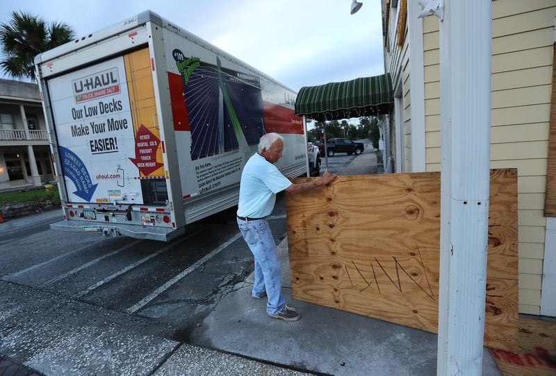 St. Marys business owner Jimmy Mock returns with his U-Haul and takes the boards down at his general store Thursday morning to begin the process of reopening after Hurricane Dorian passed Georgia’s southernmost coastal city. Mock’s business appeared to have escaped with minor wind damage from the storm.   Curtis Compton/ccompton@ajc.com