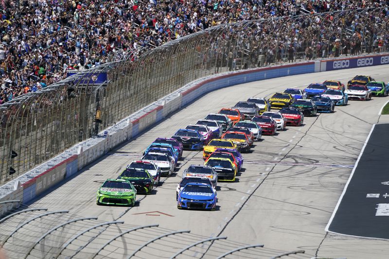 Ty Gibbs, left front, and Kyle Larson, right front, lead the field into Turn 1 after taking the green flag for the start of a NASCAR Cup Series auto race at Texas Motor Speedway in Fort Worth, Texas, Sunday, April 14, 2024. (AP Photo/Larry Papke)
