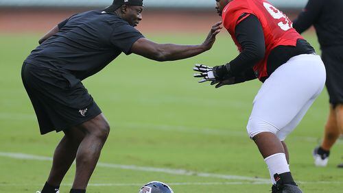 Pro Football Hall of Fame defensive end Bruce Smith, left, who has the NFL career record for quarterback sacks, works with Falcons defensive tackle Derrick Hopkins during an NFL football team practice in Flowery Branch. (Curtis Compton, ccompton@ajc.com)