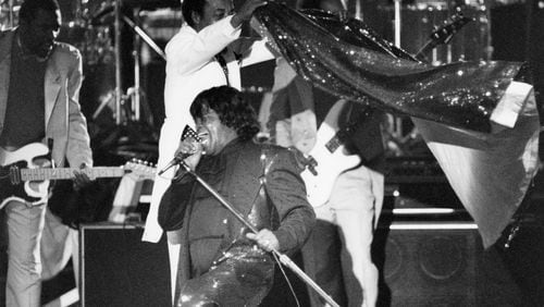 James Brown is caped by one of the band members while performing for the Auburn Avenue Festival in Atlanta, GA on April 17, 1992. (Renee Hannans/AJC staff)