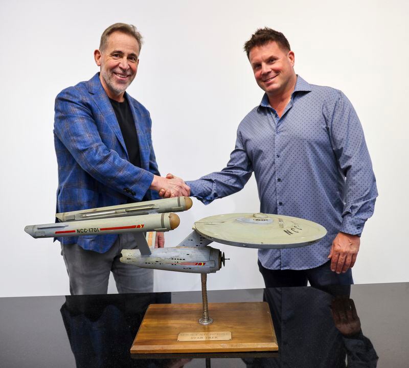 Joe Maddalena, executive vice president of Heritage Auctions, left, and Eugene “Rod” Roddenberry, the son of “Star Trek” creator Gene Roddenberry, shake hands over the recently recovered first model of the USS Enterprise at the Heritage Auctions in Los Angeles, April 13, 2024. The model — used in the original “Star Trek” television series — has been returned to Eugene, decades after it went missing in the 1970s. (Josh David Jordan/Heritage Auctions via AP)