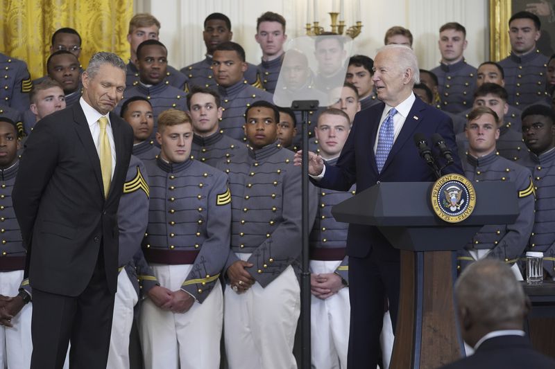 President Joe Biden speaks during an event to present the Commander-in-Chief's Trophy to the United States Military Academy Army Black Knights during an event in the East Room of the White House, Monday, May 6, 2024, in Washington, as head coach Tom Monken, left, looks on. (AP Photo/Evan Vucci)