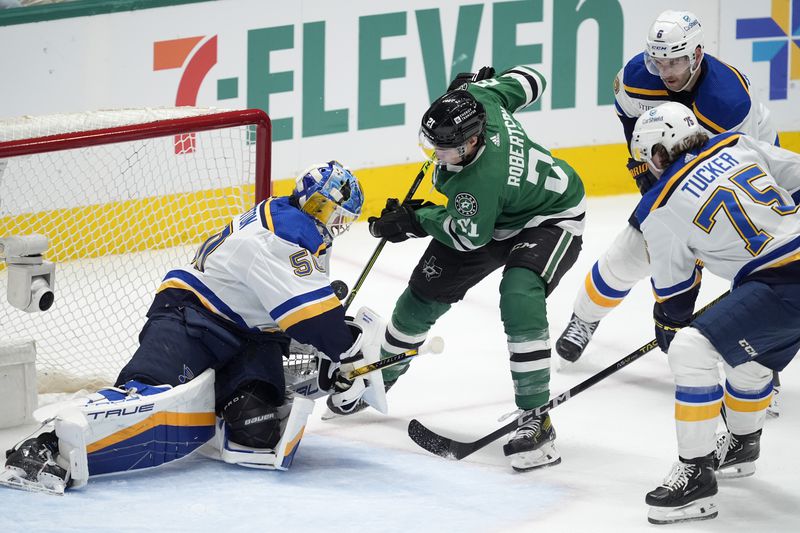 St. Louis Blues goaltender Jordan Binnington (50) blocks a shot by Dallas Stars' Jason Robertson (21) as Blues' Tyler Tucker (75) and Marco Scandella (6) help defend on the play during the first period of an NHL hockey game in Dallas, Wednesday, April 17, 2024. (AP Photo/Tony Gutierrez)