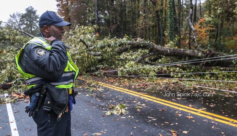 Special Police Officer P. Witter calls in barrels to be placed on Campbellton Road where a tree and power lines blocked the busy southwest Atlanta thoroughfare. JOHN SPINK / JSPINK@AJC.COM