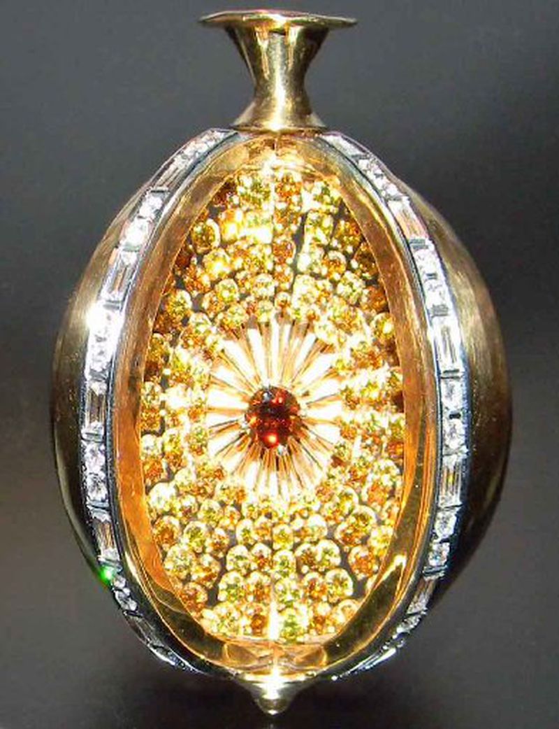 This pomegranate-shaped 18-karat gold brooch and pendant was created in 1975 by Martha Ann Gilchrist. Included in the exhibit "Jeweled Objects of Desire at Cartersville's Tellus Science Center, it was created to be worn closed in the afternoon as a brooch and then converted into the sunburst pendant for the evening. The brooch is made of 18-karat gold and set with round and baguette diamonds. When opened, six overlapping segments are folded back, creating a sunburst of 181 yellow and brown diamonds radiating from a center diamond.