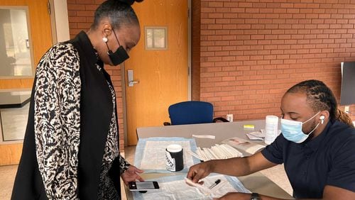William Craig (right) collects information from Orella Smith, a Morehouse School of Medicine administrative associate, before she took a self-administered COVID-19 test on campus on Nov. 11, 2021. (Eric Stirgus / eric.stirgus@ajc.com)