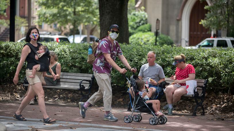 SAVANNAH, GA - June 30, 2020: A family wearing masks walk through one of Savannah's historic squares while other visitors eat on a bench near by. Savannah on Tuesday became the first major city in Georgia to require the use of face masks, setting up a potential showdown with Gov. Brian Kemp over whether local officials can take more sweeping steps than the state to contain the coronavirus. (AJC Photo/Stephen B. Morton)