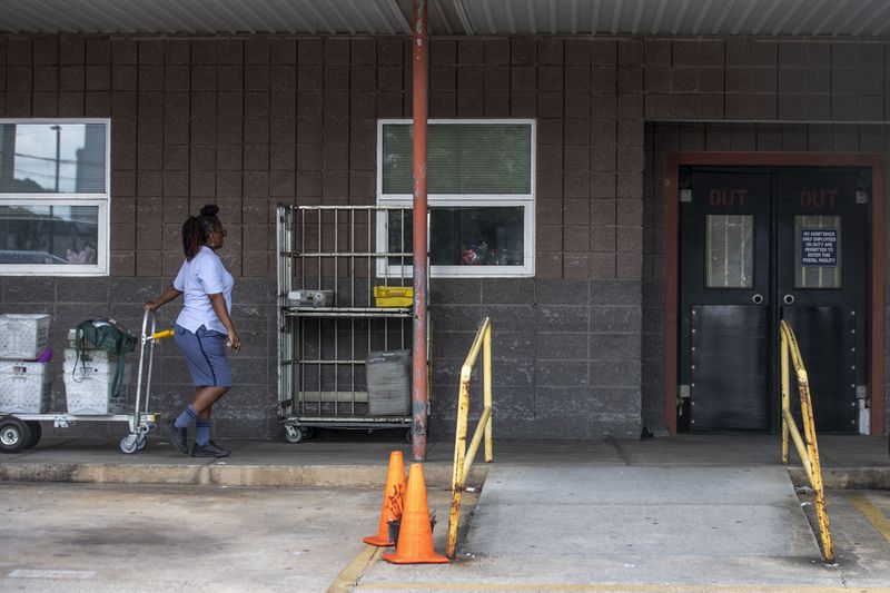 A U.S. Postal Service worker takes a cart inside the post office at 822 Ralph McGill Boulevard NE in Atlanta on Friday. (ALYSSA POINTER / ALYSSA.POINTER@AJC.COM)