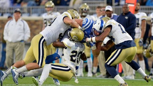 Kelton Dawson, Lawrence Austin (20) and Corey Griffin (14) of the Georgia Tech Yellow Jackets tackle Daniel Helm of the Duke Blue Devils during their game at Wallace Wade Stadium on November 18, 2017 in Durham, North Carolina.  (Photo by Grant Halverson/Getty Images)