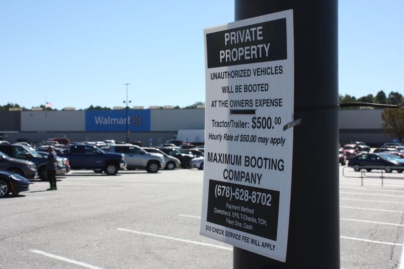 Signs in the Newnan Crossing shopping center in Newnan warn owners of “unauthorized vehicles” that are subject to booting.